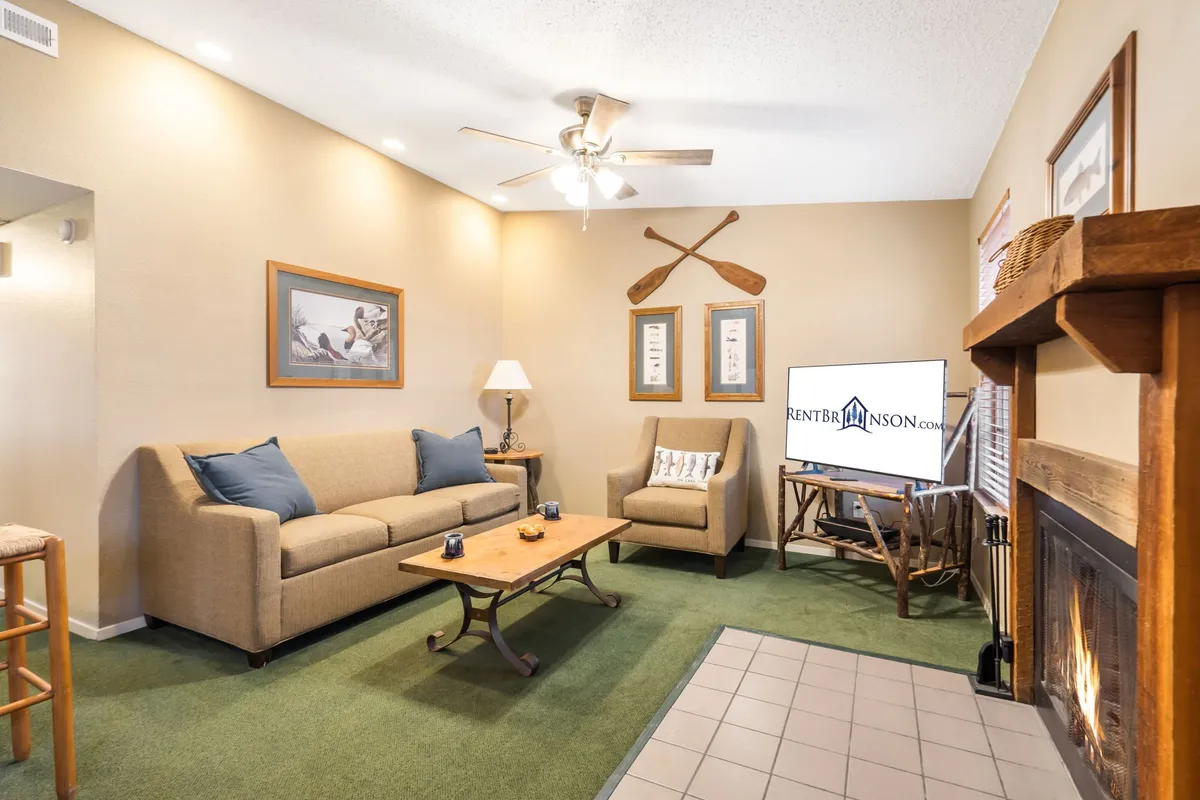 A warm and inviting living area featuring a comfortable sofa, armchair, coffee table, fireplace, and television. The space is airy and welcoming, with plush seating arranged for relaxation or socializing, and the fireplace ready to provide cozy comfort after a walk outside.