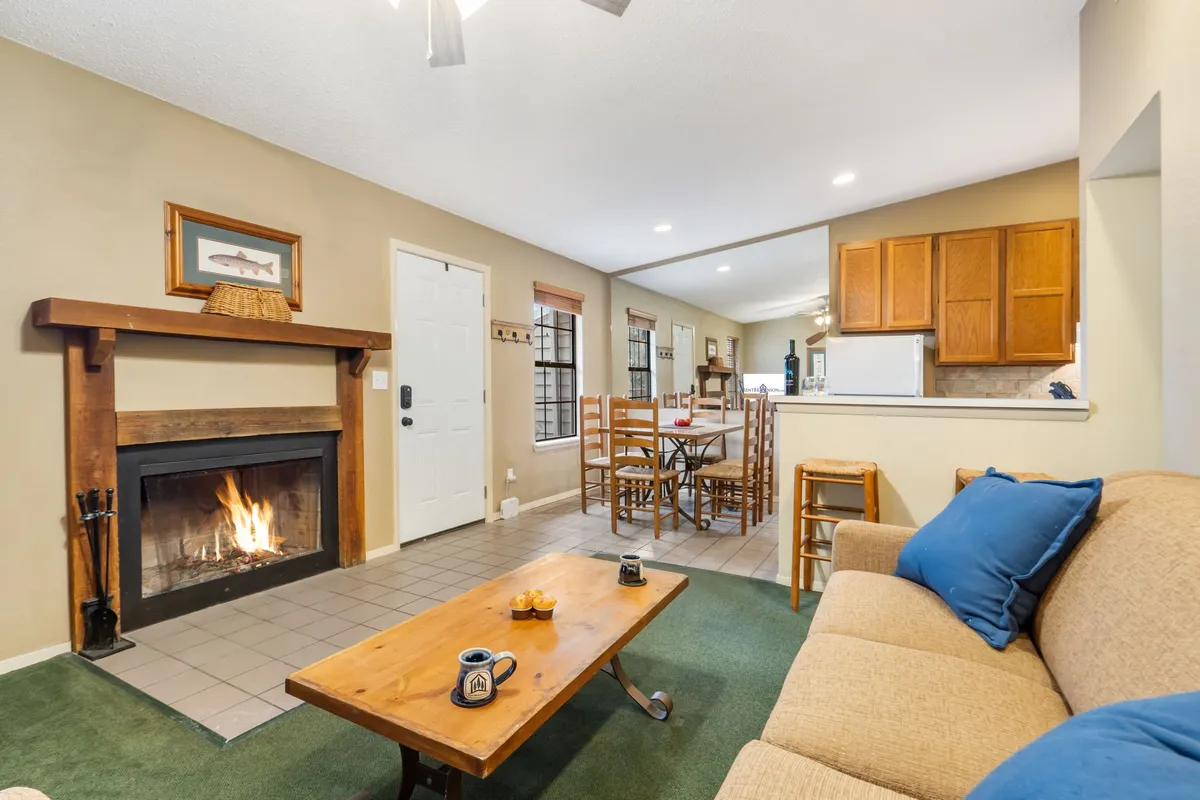 An inviting open-plan interior featuring a prominent fireplace, a comfortable sofa, a dining table set for gatherings, and a coffee table. The warm lighting and arrangement evoke a sense of togetherness and relaxation, perfectly capturing the heart of the home.