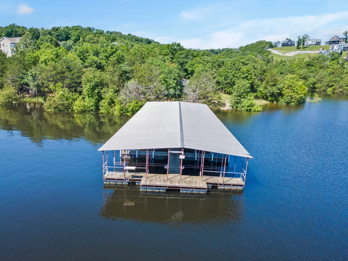 A peaceful scene featuring a quaint boathouse reflected in still waters, embraced by verdant greenery. The dock and lakeside vibes invite thoughts of fishing trips, launching boats, or unwinding by the shoreline after a day of exploration.